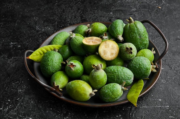 Feijoa Frutas frescas de feijoa em uma bandeja Vista superior em um fundo de pedra preta