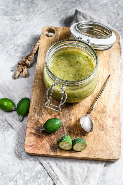 Feijoa verde à terra com açúcar em uma tábua de madeira em uma jarra de vidro.