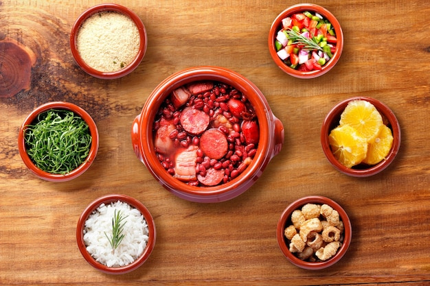 Feijoada brasileira comida tradicional da culinária do Brasil em tigela de caçarola de cerâmica sobre mesa de madeira rústica