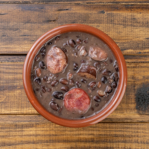 Feijoada brasileña tradicional en un recipiente sobre la mesa de madera.