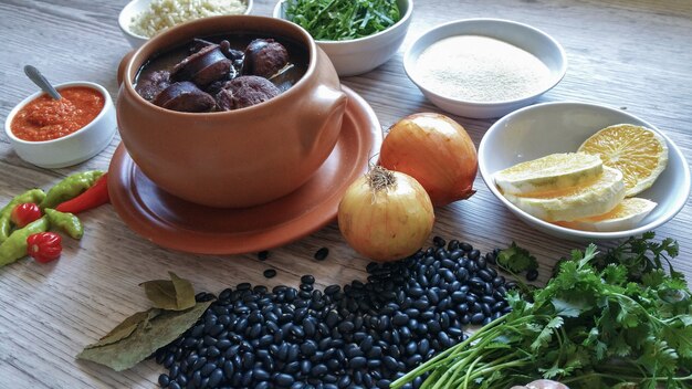 Feijoada in einer Keramikschale und ihre Zutaten. Brasilianisches Essen.