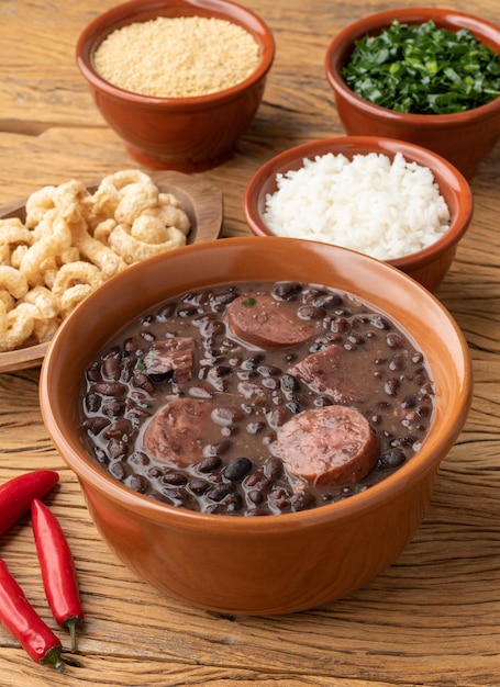 Foto feijoada típica brasileira com farofa de couve de arroz e torresmo