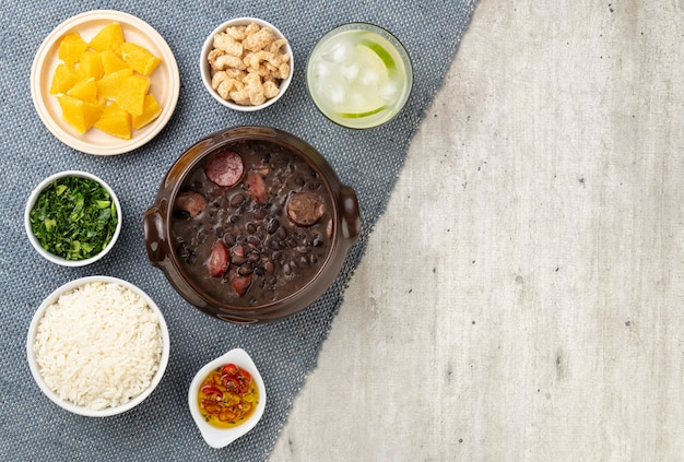 Feijoada tradicional brasileira com arroz, couve, caipirinha, laranja e copia.