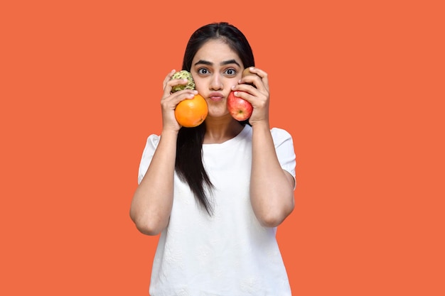 Feinschmecker Mädchen trägt weißes T-Shirt lächelnd hält Früchte mit einem Kuss indischen pakistanischen Modell weht