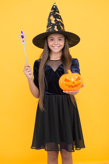 Feitiçaria e encantamento infância outono férias menina adolescente pronta para comemorar festa a fantasia diversão feliz dia das bruxas criança com chapéu de bruxa criança segura varinha mágica e abóbora assustadora Fantasmas se reúnem aqui