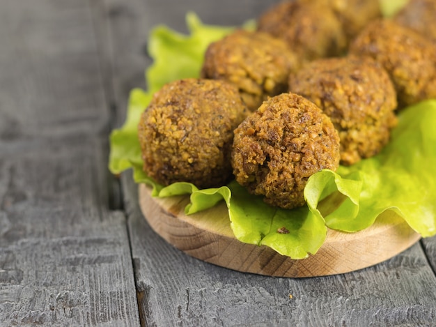 Foto feito recentemente falafel em uma folha de salada em uma tábua sobre uma mesa de madeira escura