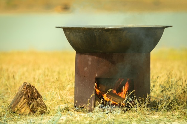 Feldküche Ein großer Kessel wird auf einem Kohlenbecken erhitzt Kochender Pilaw in der Steppe Zentralasiens