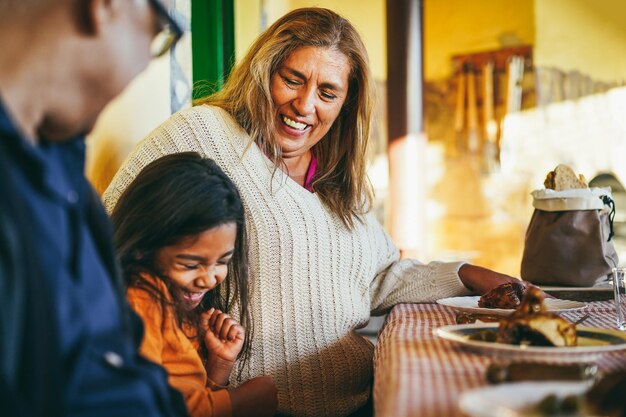 Felices abuelos latinos divirtiéndose comiendo con su nieta en el patio de casa Centrándose en la cara de la abuela