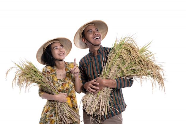 Felices agricultores asiáticos con granos de arroz