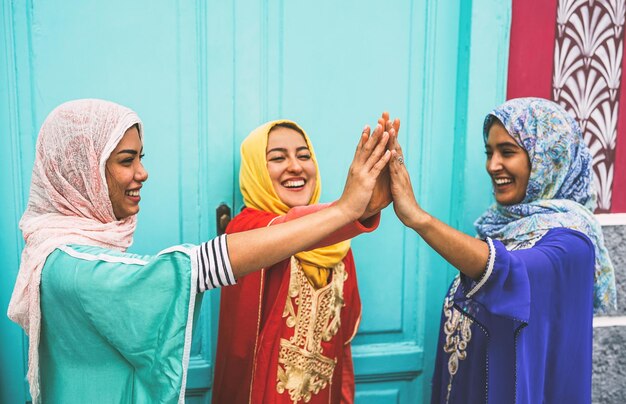 Foto felices amigas haciendo high-five mientras están de pie en la puerta