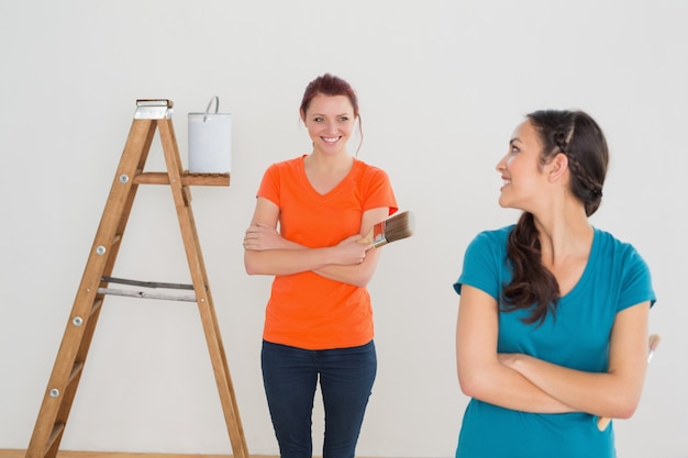 Felices amigas con pinceles y escalera