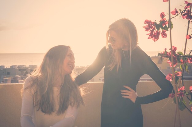 Felices amigas en la terraza contra el cielo