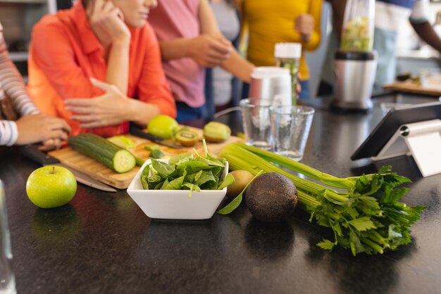 Foto felices amigos diversos cocinando y sonriendo juntos en la cocina