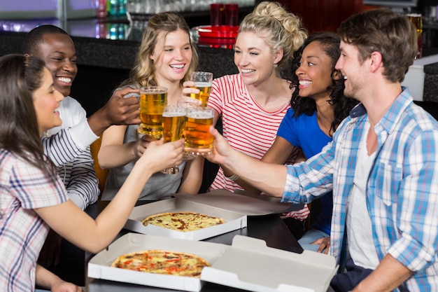 Felices amigos tomando una copa y pizza