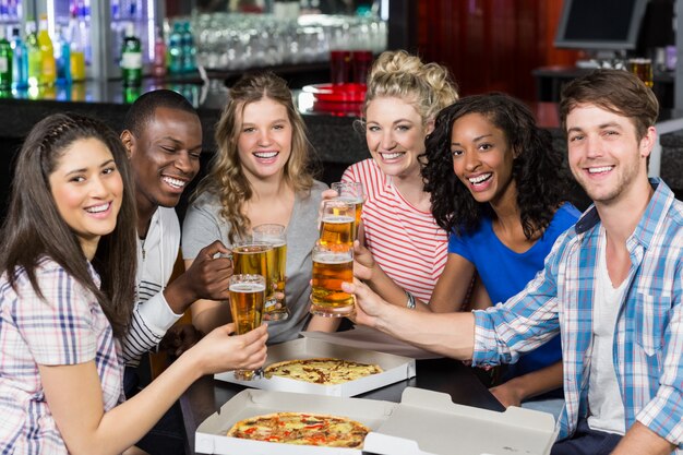 Felices amigos tomando una copa y pizza