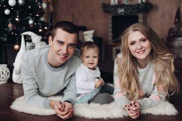 Felices besos padres y bebé entre regalos de Navidad