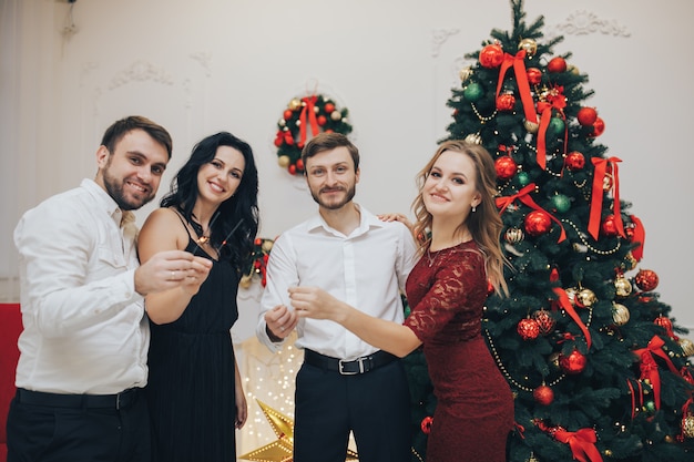 Felices chicos y chicas disfrutando de la fiesta de Año Nuevo con luces de Bengala