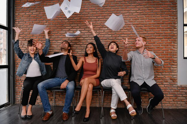 Foto felices colegas de negocios arrojando documentos durante una reunión en la oficina