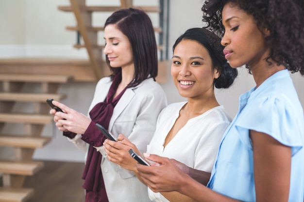 Felices colegas de negocios femeninos mediante teléfono móvil