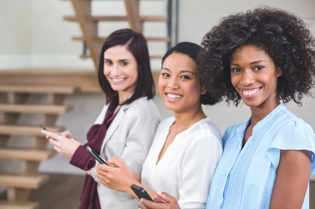 Felices colegas de negocios femeninos mediante teléfono móvil