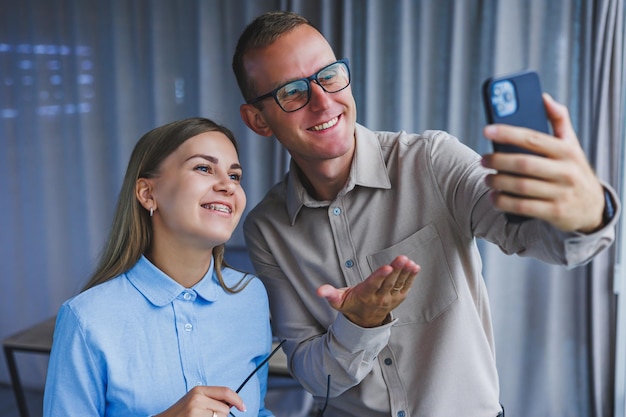 Felices colegas de negocios trabajando juntos en la oficina y usando el teléfono Los colegas se toman una selfie durante un descanso