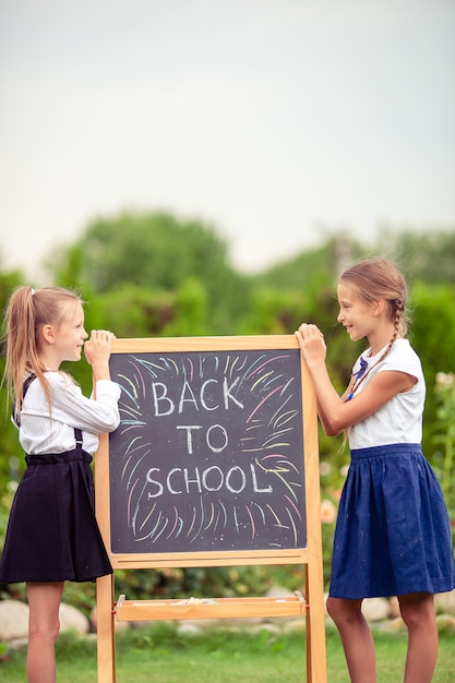 Felices colegialas con una pizarra al aire libre