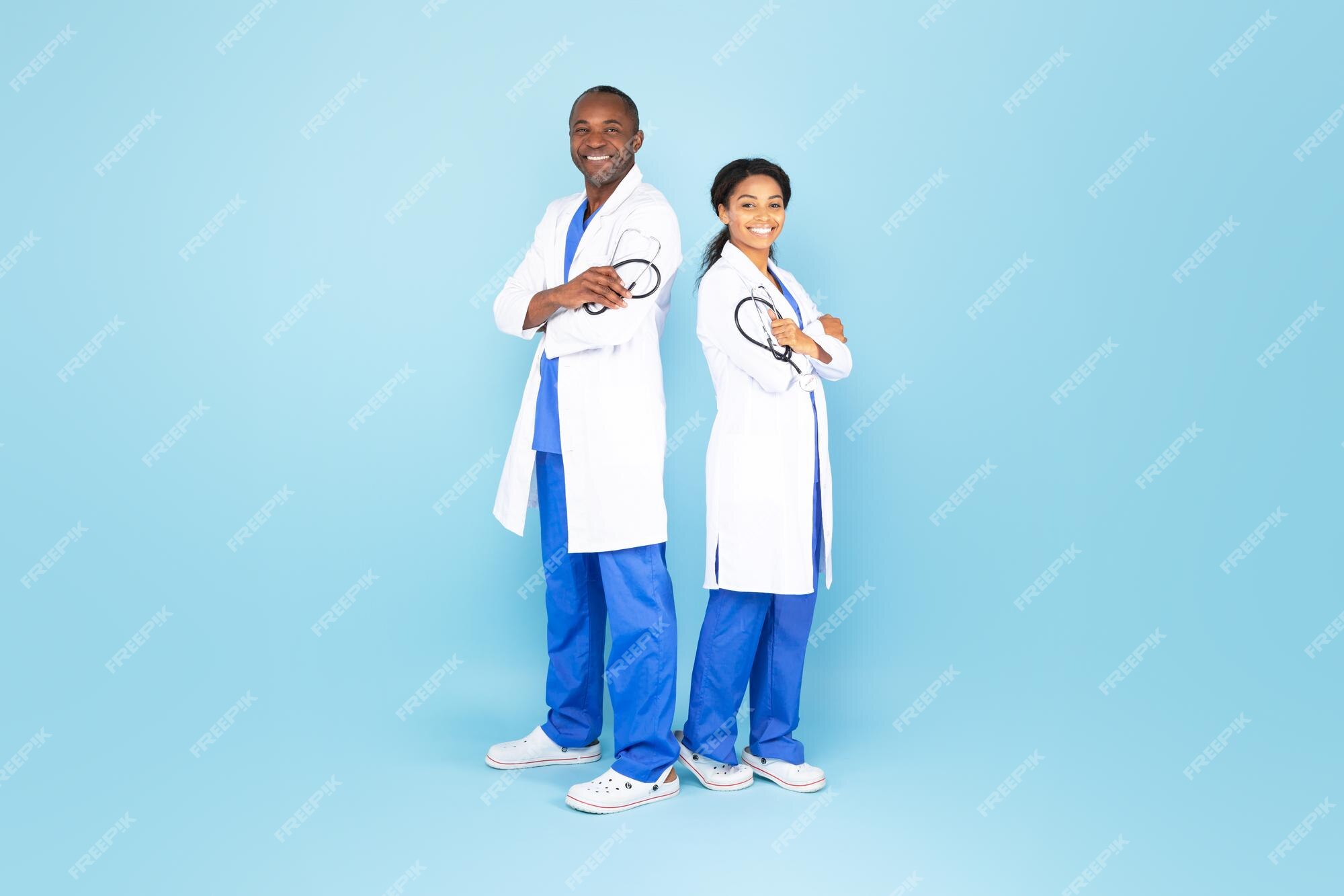 Felices y confiados terapeutas masculinos y femeninos con batas blancas posando con los brazos cruzados aislados en fondo azul Foto Premium