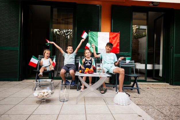 Felices cuatro niños con banderas italianas celebrando el Día de la República de Italia