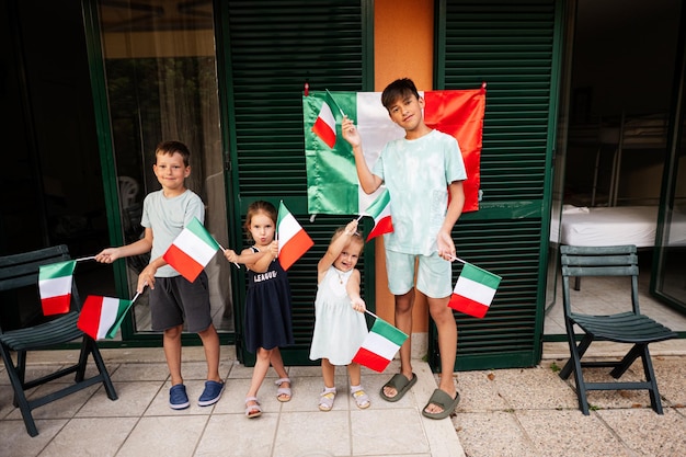 Felices cuatro niños con banderas italianas celebrando el Día de la República de Italia