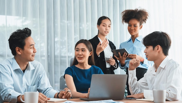 Felices y diversos empresarios trabajan juntos discutiendo en la oficina corporativa El trabajo en equipo profesional y de diversidad discute el plan de negocios en el escritorio con una computadora portátil Oficinista multicultural moderno Concord