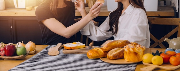 Felices dos mujeres jóvenes que buscan una computadora portátil mientras cocinan juntas en la cocina de su casa Dos jóvenes lesbianas diversas que pasan tiempo juntas LGBT y el concepto de identidad de género