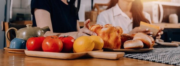 Felices dos mujeres jóvenes que buscan una computadora portátil mientras cocinan juntas en la cocina de su casa Dos jóvenes lesbianas diversas que pasan tiempo juntas LGBT y el concepto de identidad de género