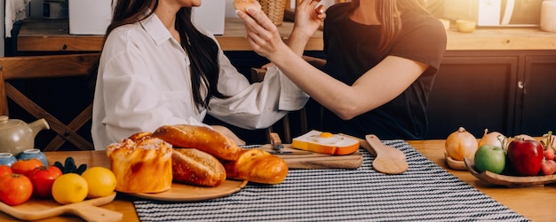 Felices dos mujeres jóvenes que buscan una computadora portátil mientras cocinan juntas en la cocina de su casa Dos jóvenes lesbianas diversas que pasan tiempo juntas LGBT y el concepto de identidad de género