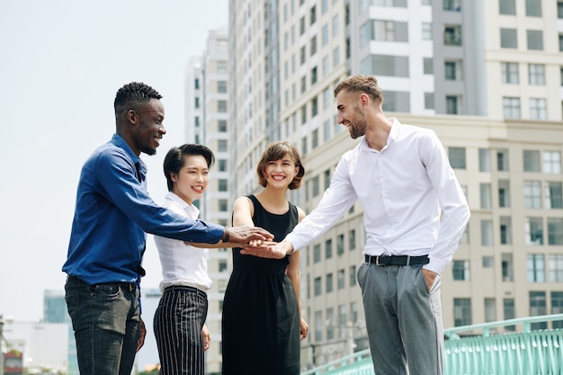 Felices ejecutivos de negocios apilando las manos