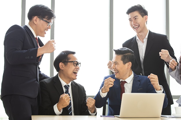 Foto felices empresarios asiáticos vitoreando juntos celebran el éxito del proyecto compañeros de trabajo trabajo en equipo