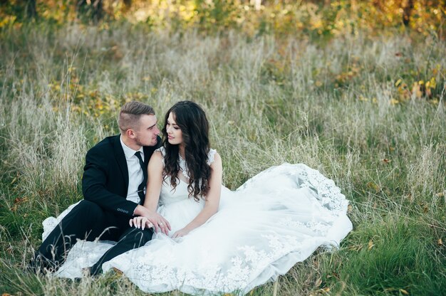 Felices y enamorados novios en el parque de otoño el día de su boda