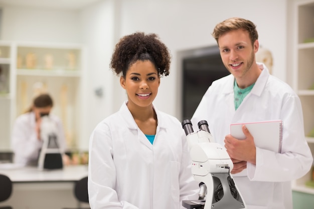 Felices estudiantes de medicina que trabajan con microscopio