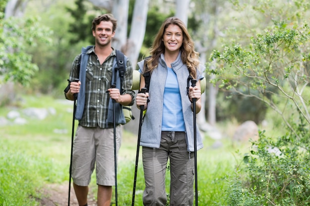 Felices excursionistas caminando con bastones en el bosque