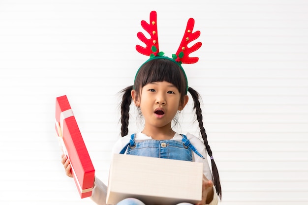 Felices fiestas y Navidad Niña linda alegre celebración actual caja de regalo en la sala blanca.