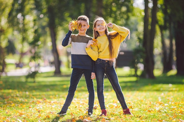 Foto felices gemelos adolescentes niño y niña posando abrazándose en el parque otoño