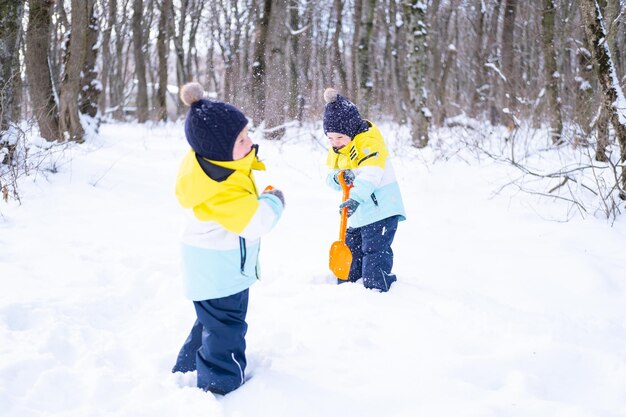 Felices hermanos gemelos jugando con nieve en la naturaleza invernal. Niños divirtiéndose al aire libre