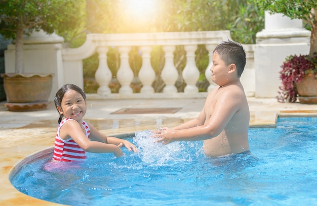 Felices hermanos y hermanas juegan en la piscina,