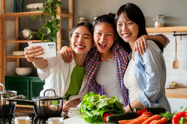 Felices y hermosas amigas chinas uniéndose en casa y cocinando una deliciosa comida juntas