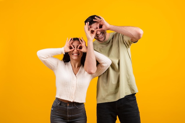 Felices hombres y mujeres milenarios del Medio Oriente se divierten haciendo anteojos con las manos disfrutan del tiempo libre juntos