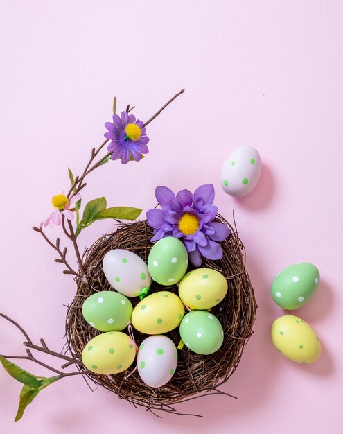 Felices huevos de color pastel de Pascua en un nido sobre fondo rosa