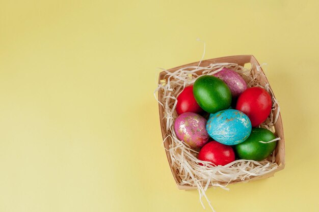 Felices huevos de Pascua fondo amarillo Huevos decorados con brillo dorado en la cesta para el afiche de promoción de tarjetas de felicitación Espacio de copia