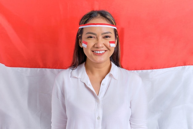 Felices jóvenes asiáticas celebran el día de la independencia de Indonesia con la bandera de Indonesia como fondo