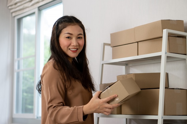 Felices jóvenes empresarios asiáticos están organizando cajas para entregar productos a los clientes.