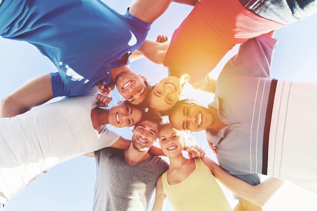 Felices los jóvenes de pie en círculo contra el cielo azul