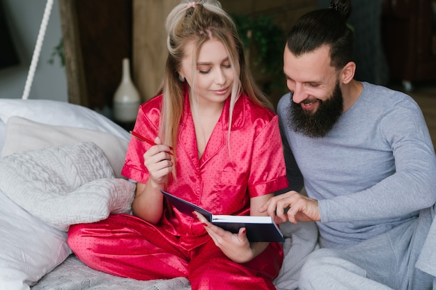 Felices juntos. Planificación de fin de semana de vacaciones. Pareja joven en pijama haciendo planes.